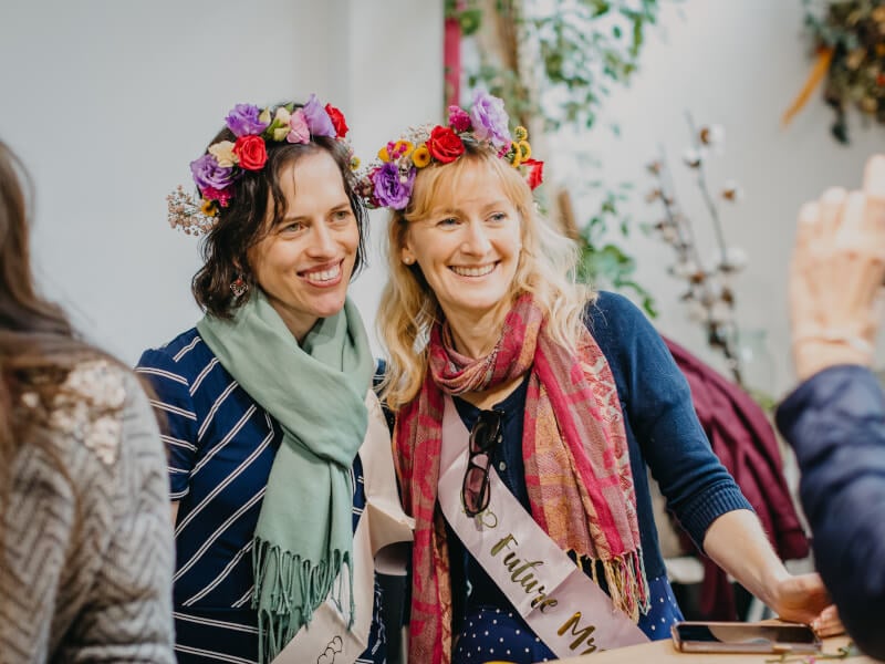 Two women wearing flower crowns smiling for a photo